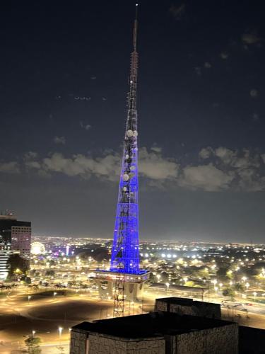 Una torre alta iluminada en azul por la noche en Nobile Suites, Flats Rocha, en Brasilia