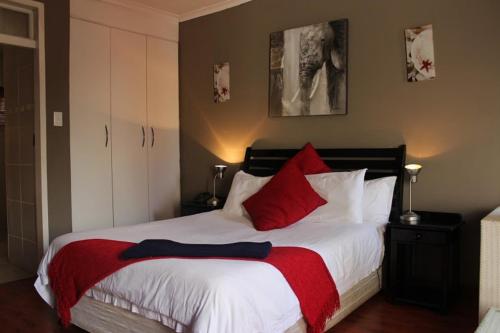 a bedroom with a large bed with red pillows at Flamboyant Guest Lodge in Johannesburg