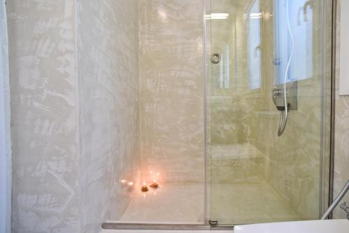 una ducha con una puerta de cristal con una vela dentro en Mavres Luxury Studio, en Ágios Matthaíos