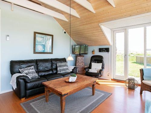 a living room with a black leather couch and a table at 8 person holiday home in Løkken-By Traum in Løkken