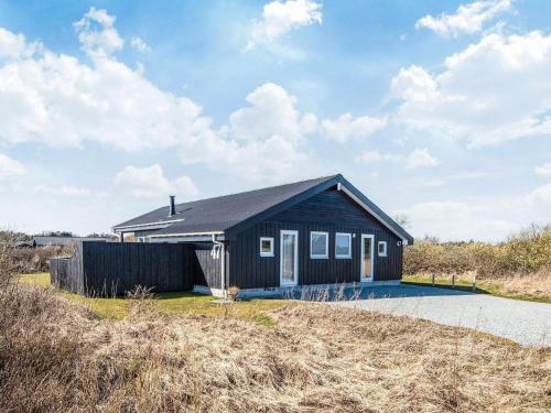 a small black house on the side of a road at 6 person holiday home in Hirtshals-By Traum in Hirtshals