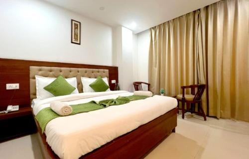 a bedroom with a large bed with green and white pillows at Hotel Royal aroma by Shradha Residency in Rāiwāla
