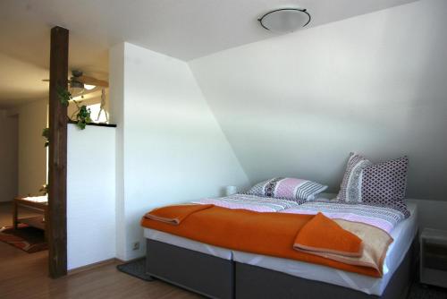 a bedroom with a bed with an orange blanket at Ferienwohnung Maul 