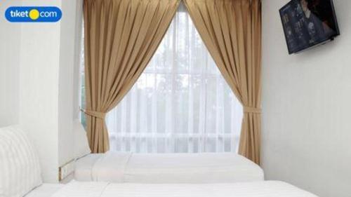 a bedroom with a window with a bed and curtains at An Hotel Jakarta in Jakarta