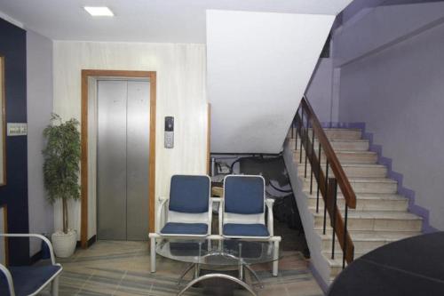 two blue chairs sitting in a hallway with stairs at Krishna Krupa in Coimbatore
