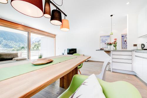 a kitchen with a long wooden table and green chairs at Appartement Valbona Blick by A-Appartments in Bürserberg