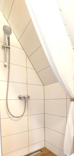 a shower in a bathroom with white tiled walls at Vier Winde Usedom - Ferienanlage in Krummin