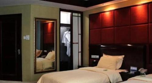 a bedroom with two beds and a large mirror at Chinflux Mandarin Hotel in Dongguan