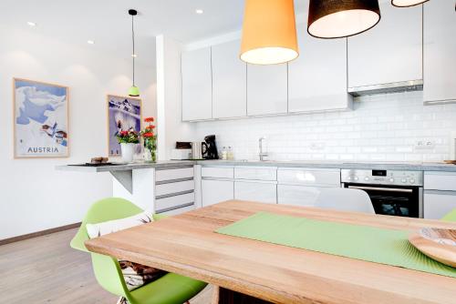 a kitchen with a wooden table and white cabinets at Appartement Valbona Blick by A-Appartments in Bürserberg