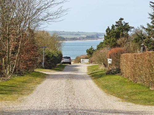 a gravel road with a car parked on the side of a lake at 7 person holiday home in Struer-By Traum in Humlum