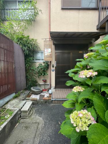 an entrance to a house with a gate and flowers at Koto Next Door in Otsu