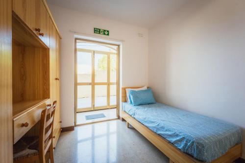 a small bedroom with a bed and a window at Bright 3-Bed Apartment with Outdoor Dining Mellieha in Is-Sellum