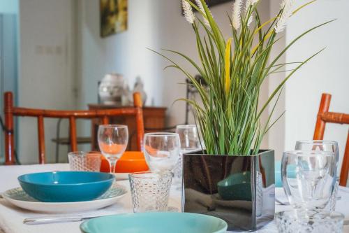 a table with glasses and a potted plant on it at Bright 3-Bed Apartment with Outdoor Dining Mellieha in Is-Sellum