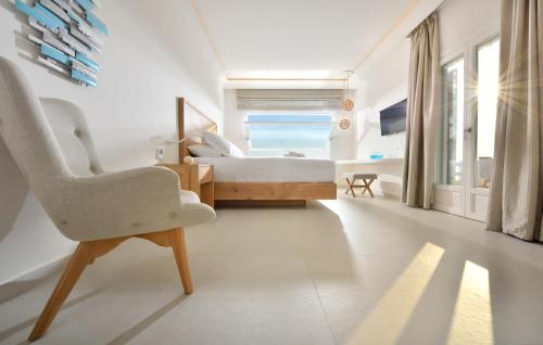 a white bedroom with a bed and a chair at Anax Resort and Spa in Agios Ioannis Mykonos