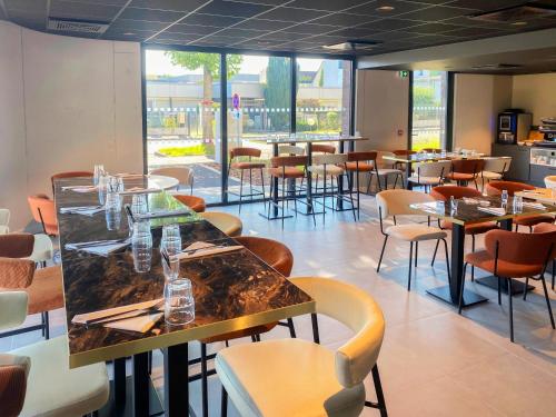 a dining room with tables and chairs and windows at Nemea Appart Hotel Coeur Europe Strasbourg Illkirch in Illkirch-Graffenstaden