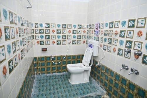 a bathroom with a toilet with a tiled wall at Sai Padma Guest House in Konārka