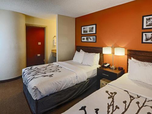 a hotel room with two beds with orange walls at Sleep Inn & Suites Spring Lake - Fayetteville near Fort Bragg in Spring Lake