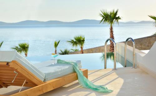 a swimming pool with a bed next to the ocean at Anax Resort and Spa in Agios Ioannis Mykonos
