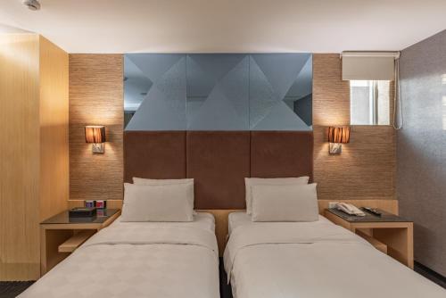 two beds in a small room with two lamps at Hotel G7 Taipei in Taipei