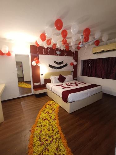 a bedroom with a bed with red balloons on the ceiling at Presidency Landmark in Daman