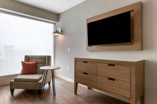 a living room with a tv and a chair at Cambria Hotel Austin Airport in Austin