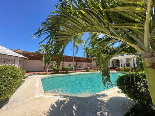 a swimming pool with a palm tree in front of a house at Glamorous Getaway PM in Malindi
