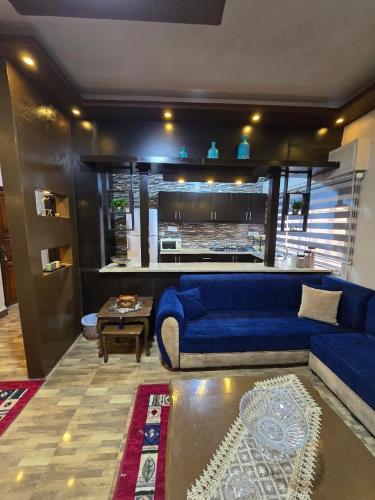 a living room with a blue couch and a kitchen at Deluxe Furnished Studio Jubaiha in Amman