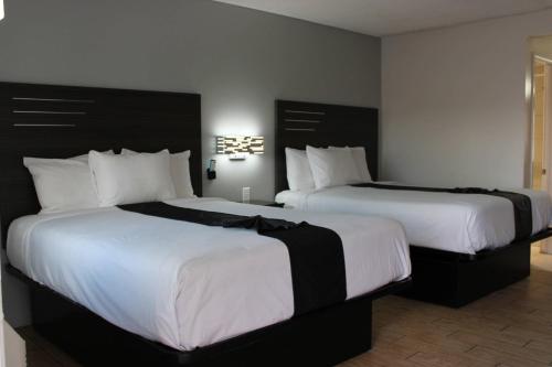 two beds in a hotel room with white sheets at Rodeway Inn Yuma Downtown in Yuma