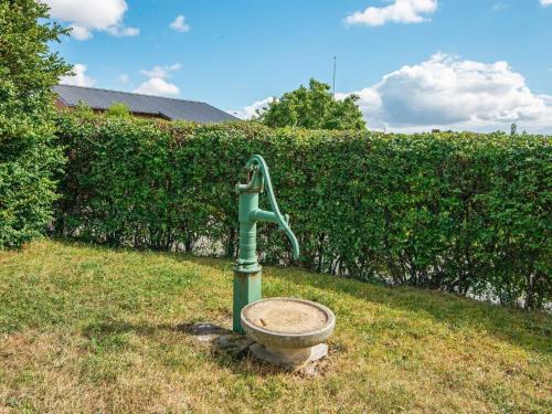 a water fountain in the grass in front of a hedge at Enchanting Cottage in Oksbol Oasis-By Traum in Nordborg