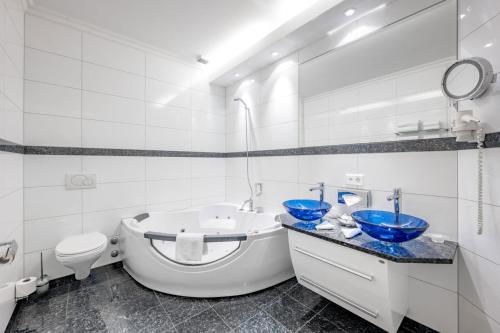 a bathroom with a tub and a sink and a toilet at Turmhotel Victoria Davos in Davos