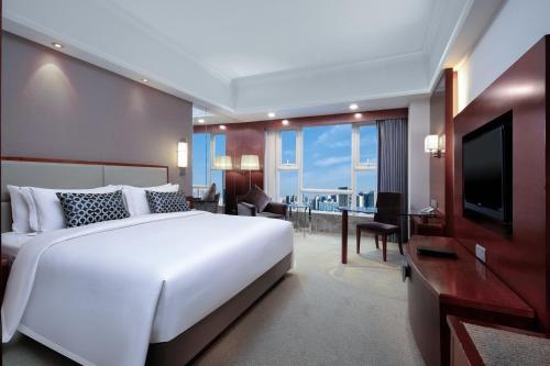 a bedroom with a large white bed and a television at Grand Sun City Hotel-Located city center Metro Access in Changsha
