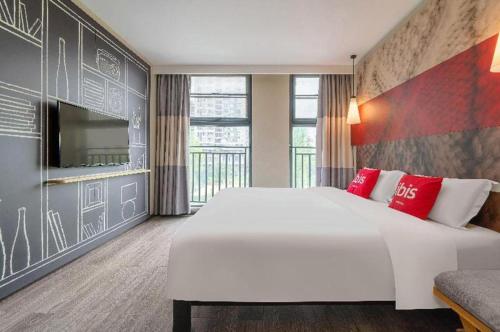 une chambre avec un grand lit blanc et une télévision dans l'établissement ibis Chengdu East Railway Station Hotel, à Chengdu