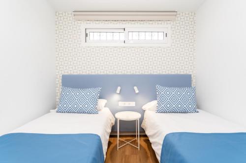 two beds in a room with blue and white at Alsol Nara in Playa del Ingles