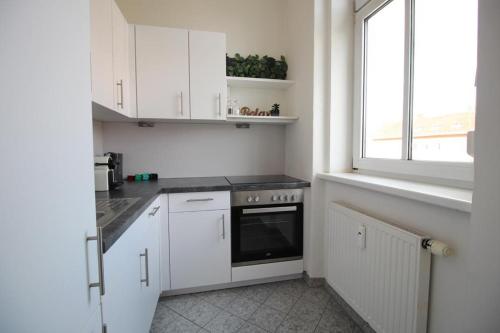 une cuisine avec des armoires blanches et une fenêtre dans l'établissement Moderne & zentrale Citywohnung nahe Stadthalle, Messe & Sportpark, à Graz