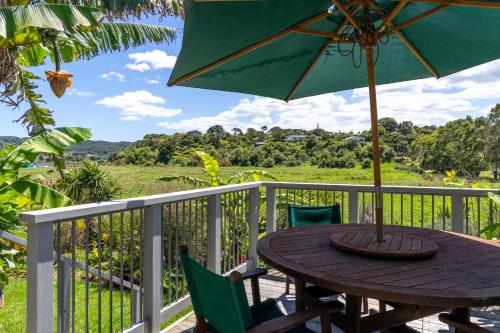 einen Holztisch mit Sonnenschirm auf dem Balkon in der Unterkunft Pineapple Palace Studio in Raglan