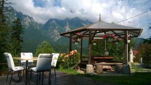 a wooden gazebo with chairs and a table with a view of mountains at Vila Alunis in Buşteni