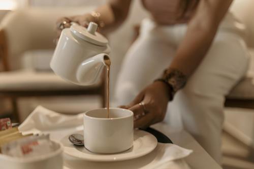 a woman pouring coffee into a cup on a table at Biznotel by Pride Surat in Surat