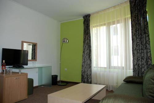 a living room with a couch and a tv at Green Hisar Hotel Family in Hisarya