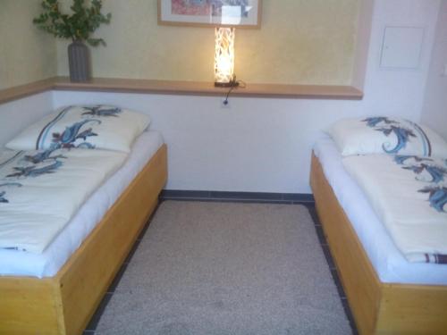two beds in a room with a light on the wall at Pension Gasthaus zum Pegel in Naumburg