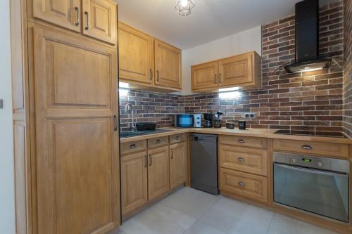 a kitchen with wooden cabinets and a brick wall at Gîtes de l'Orée du Bois - Torpes in Torpes
