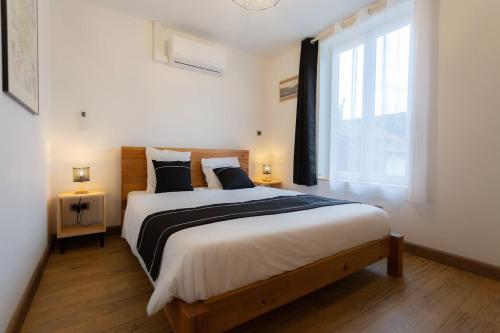 a bedroom with a large bed with a large window at Gîtes de l'Orée du Bois - Torpes in Torpes