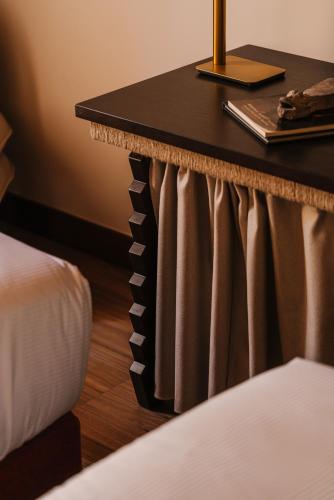 a nightstand with a table and a bed in a room at Palacio De Godoy Caceres, Curio Collection By Hilton in Cáceres