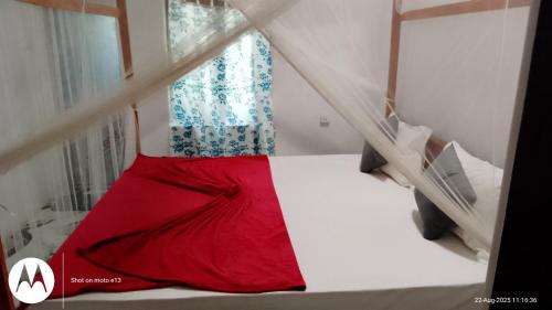 a bed with a red dress on it in a room at Hiriketiya Lima Homestay in Dickwella
