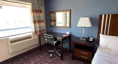 a hotel room with a desk and a bed and a window at Econo Lodge Inn & Suites in Enid