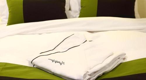 a white blanket on a bed with green pillows at KT&G Sangsangmadang Chuncheon Stay (Korea Quality) in Chuncheon
