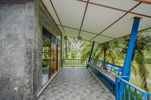 a balcony of a house with a blue railing at บ้านสวนลุงหวัด พังงา in Takua Thung