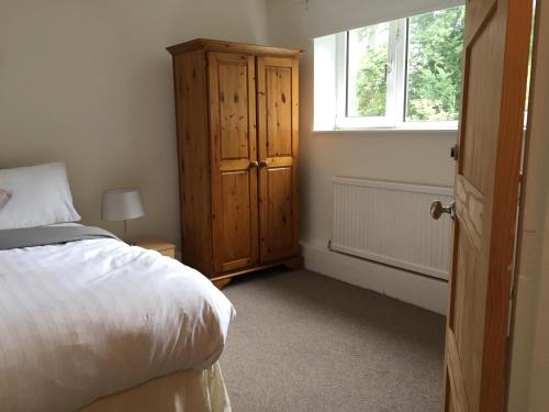 a bedroom with a bed and a dresser and a window at The Tudors Three Bedroom Apartment in St. Albans