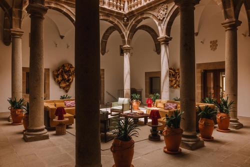 a lobby with couches and potted plants in a building at Palacio De Godoy Caceres, Curio Collection By Hilton in Cáceres