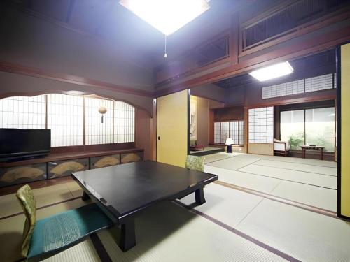 a living room with a table and chairs and a tv at Suigetsurou Hotel in Takaoka
