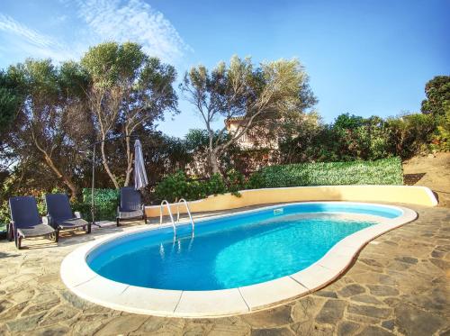 a swimming pool in a yard with two chairs at Villa Blu splendida villa con piscina - Stintino Sardegna in Cuile Pazzoni